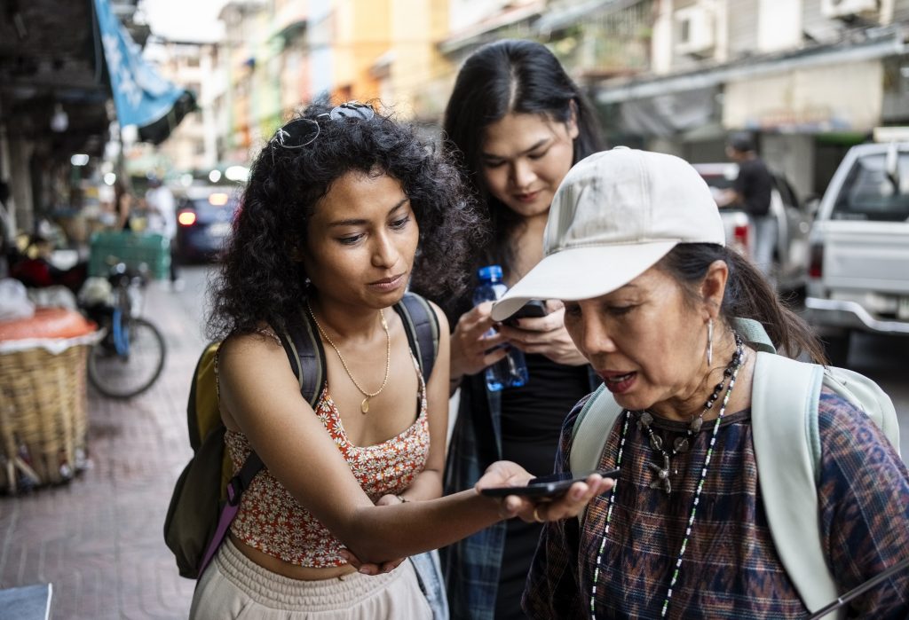 Female tourists and tour guide using phone for translation on city tour